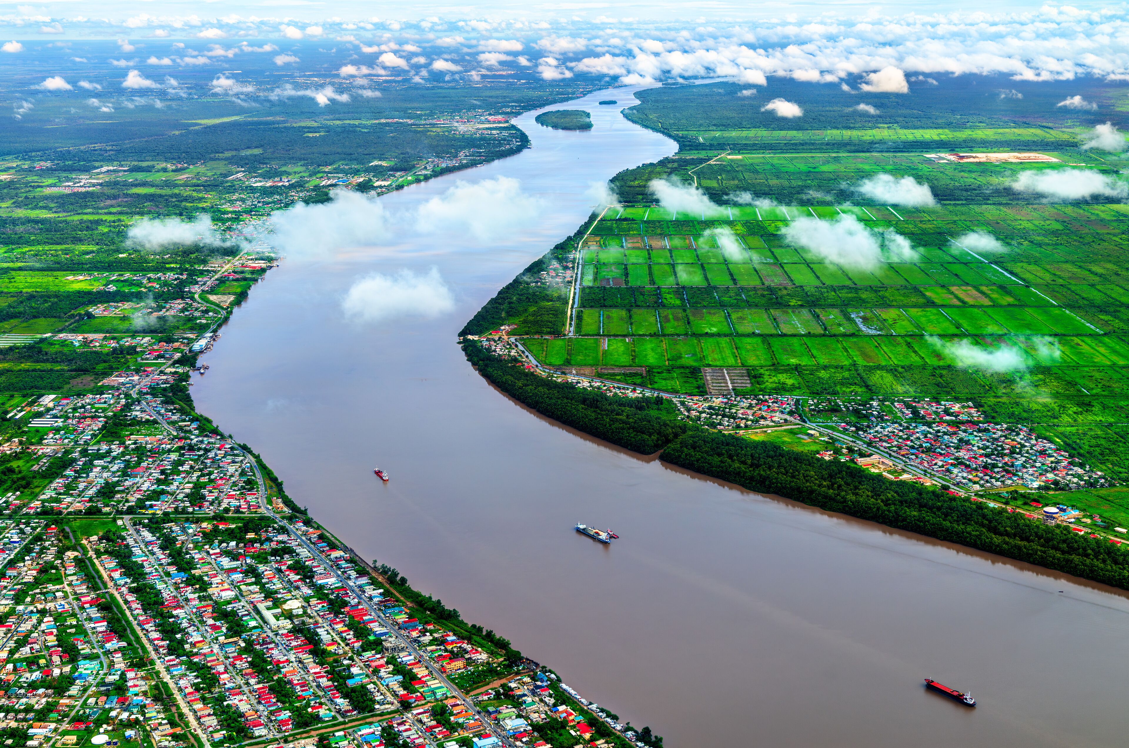 A river winding through a densely populated area with green fields and a small town.