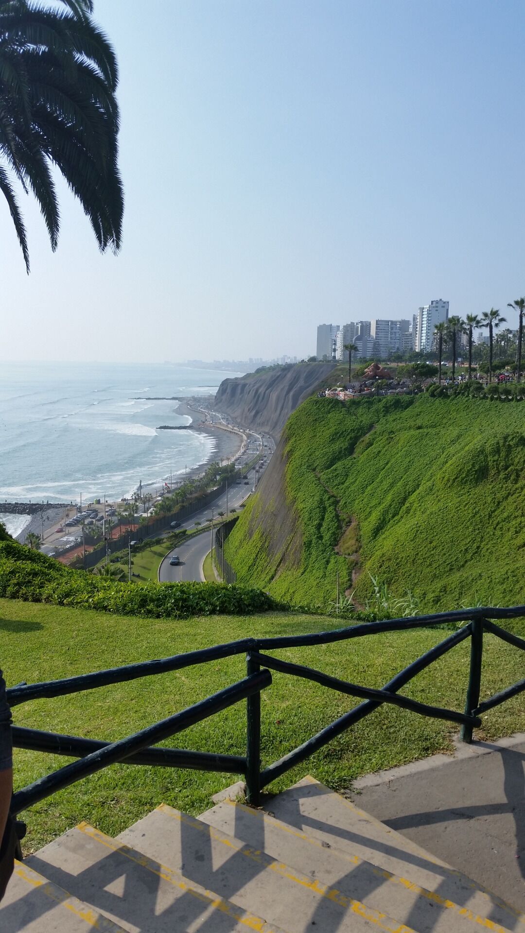 A coastal cityscape with a prominent cliff, a beach, and a road leading to the beach.