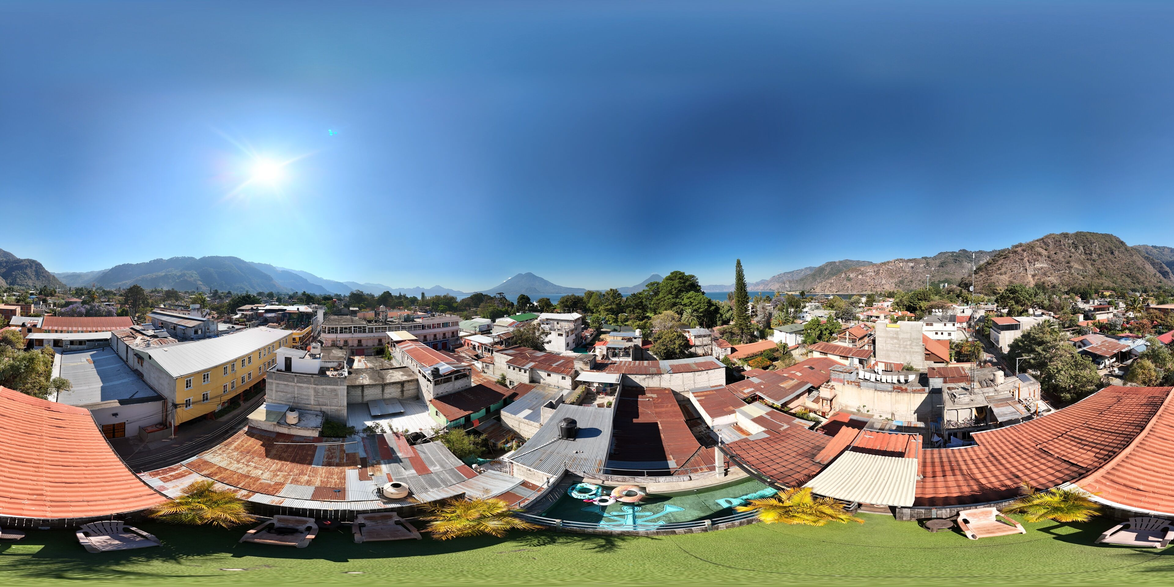 A coastal town with red-roofed buildings, a beach, and mountains in the background.