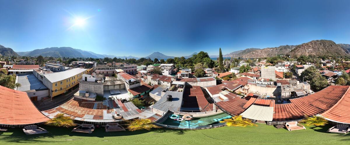 A coastal town with red-roofed buildings, a beach, and mountains in the background.