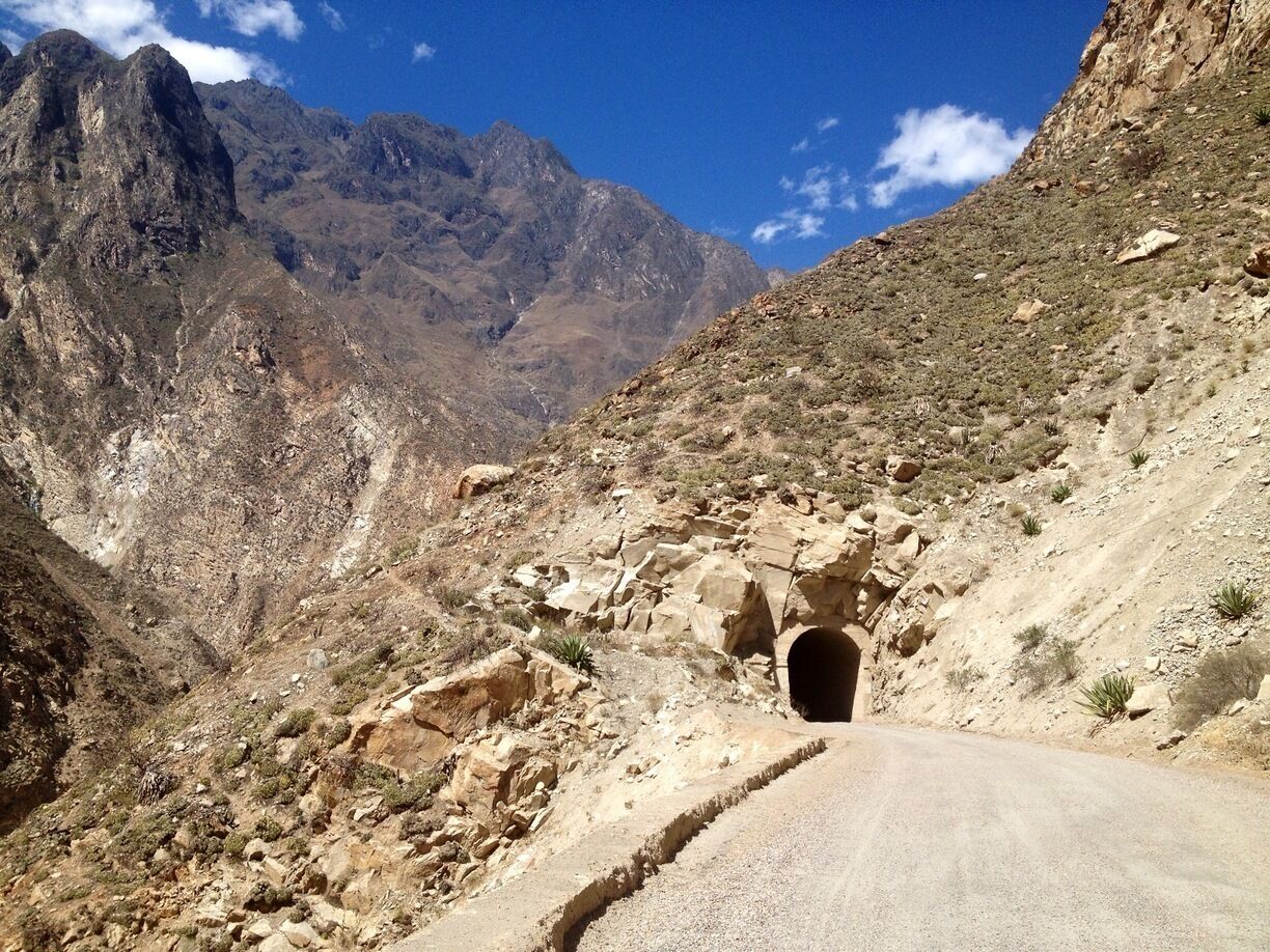 A mountainous landscape with a road leading to a tunnel.
