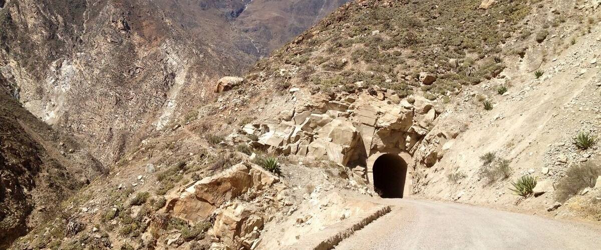 A mountainous landscape with a road leading to a tunnel.
