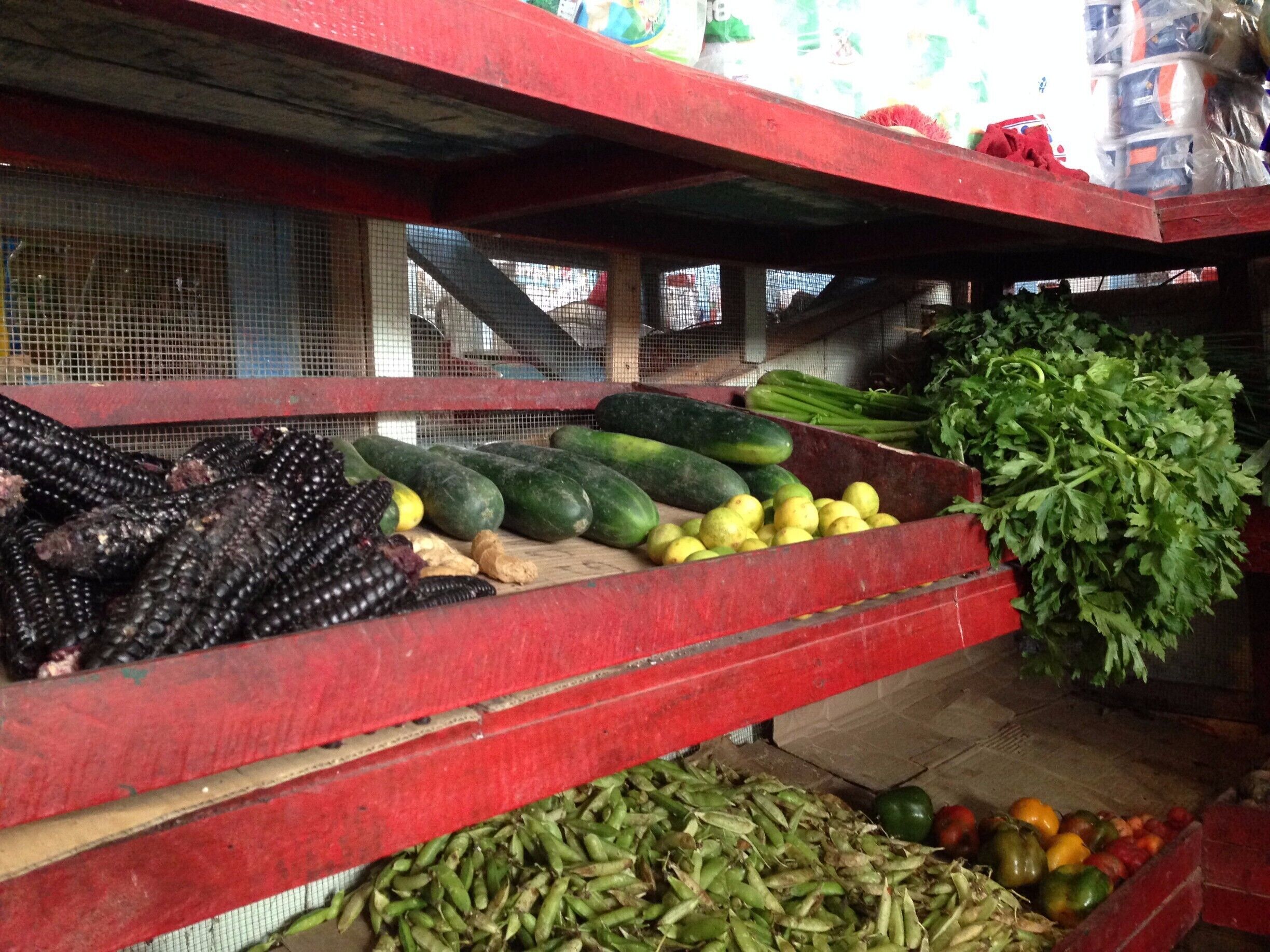 A market stall with various vegetables like corn, cucumbers, and green beans.