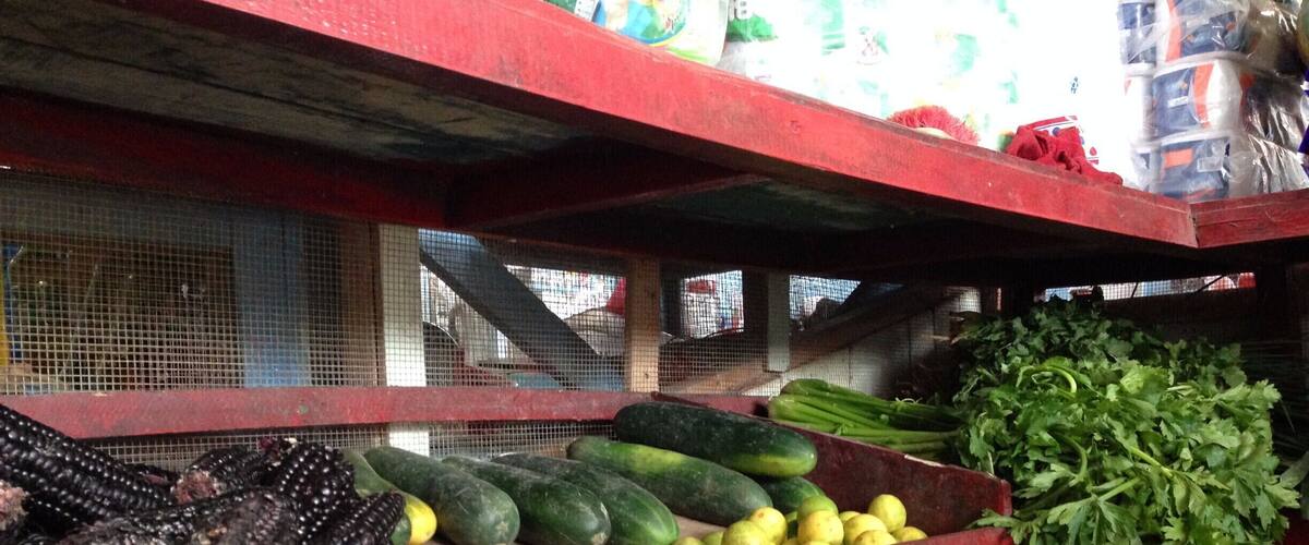 A market stall with various vegetables like corn, cucumbers, and green beans.