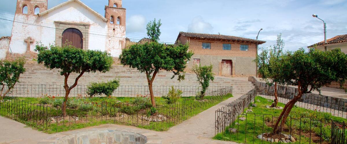 A historic church with bell towers, a stone pathway, and a small garden with trees and flowers.