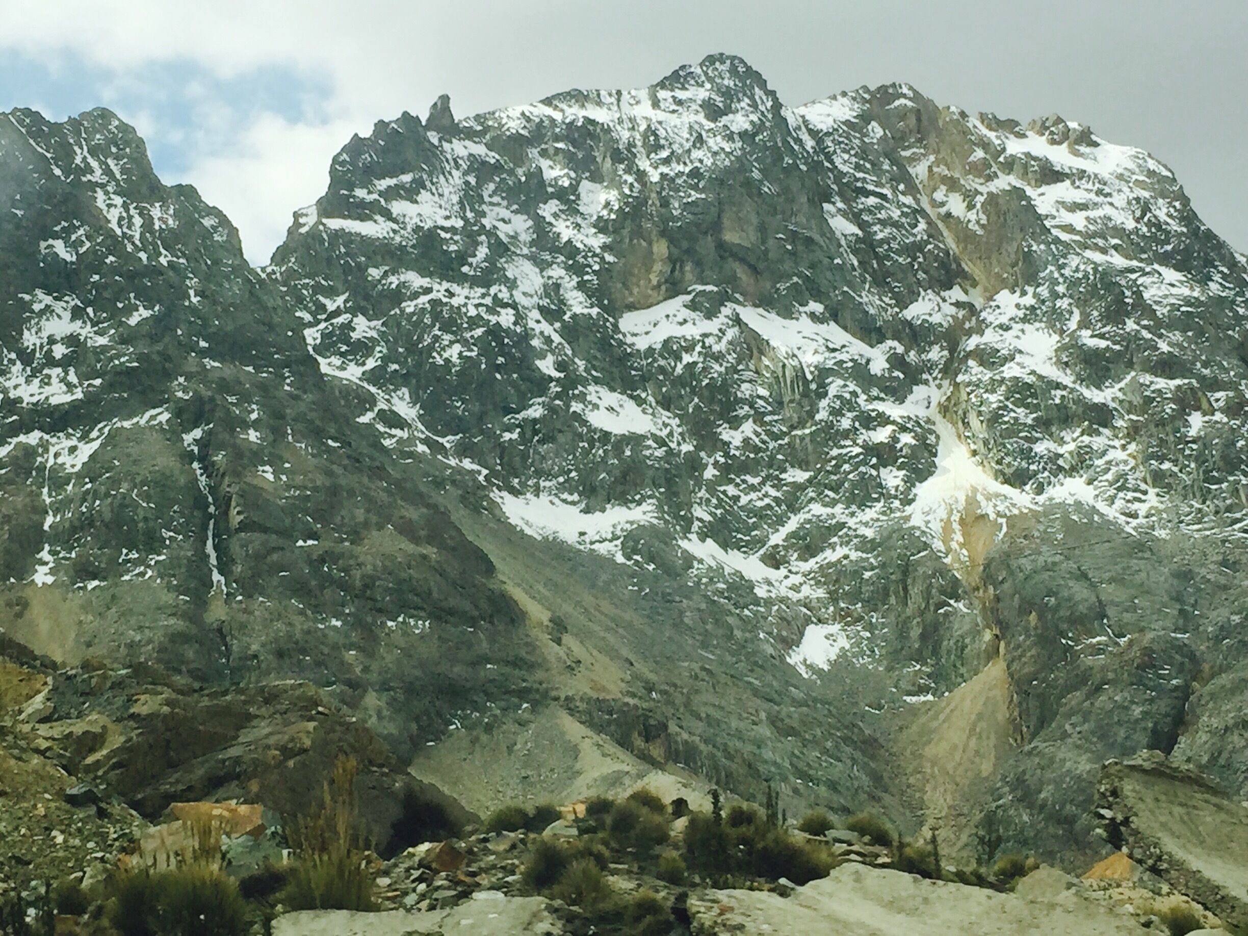 A rugged mountain landscape with snow-capped peaks and rocky terrain.