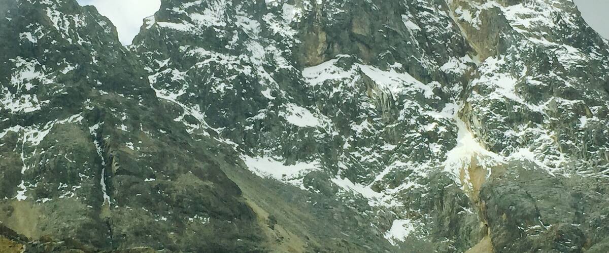 A rugged mountain landscape with snow-capped peaks and rocky terrain.