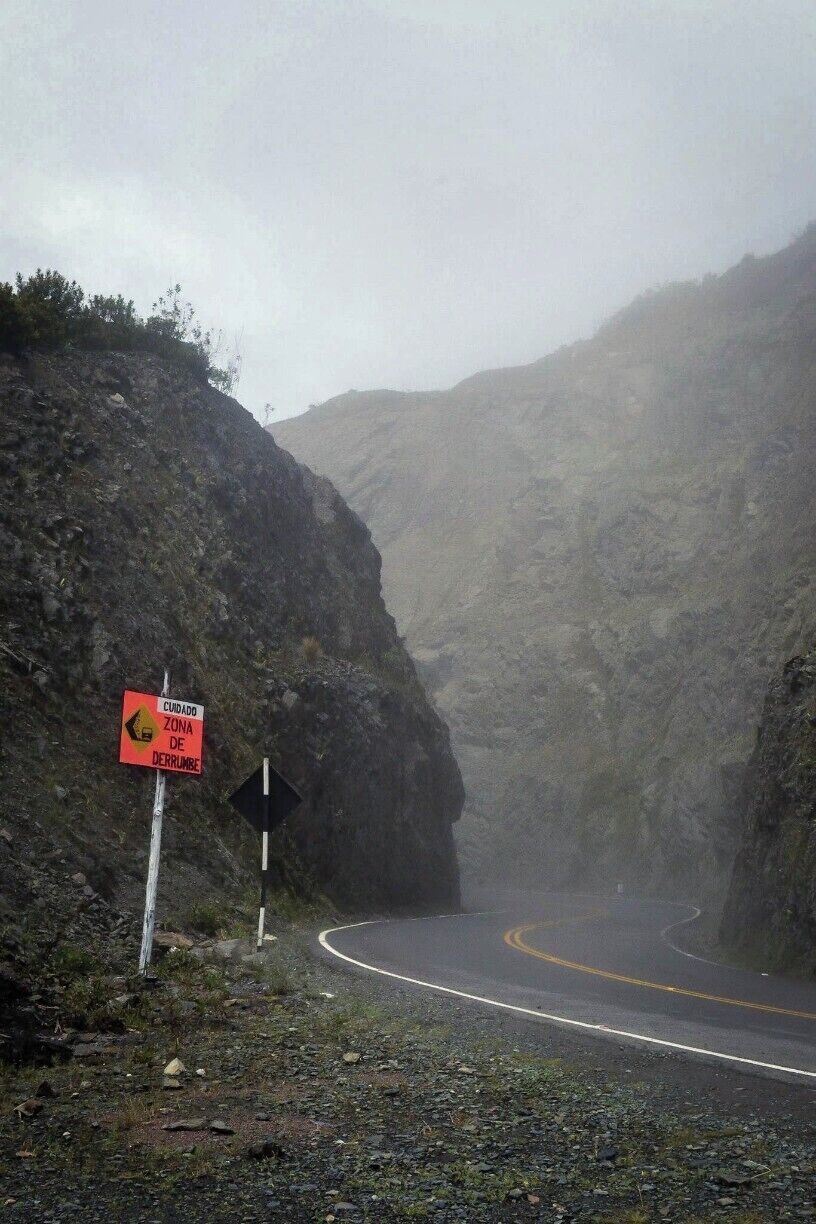 A winding mountain road with a warning sign for a steep descent.