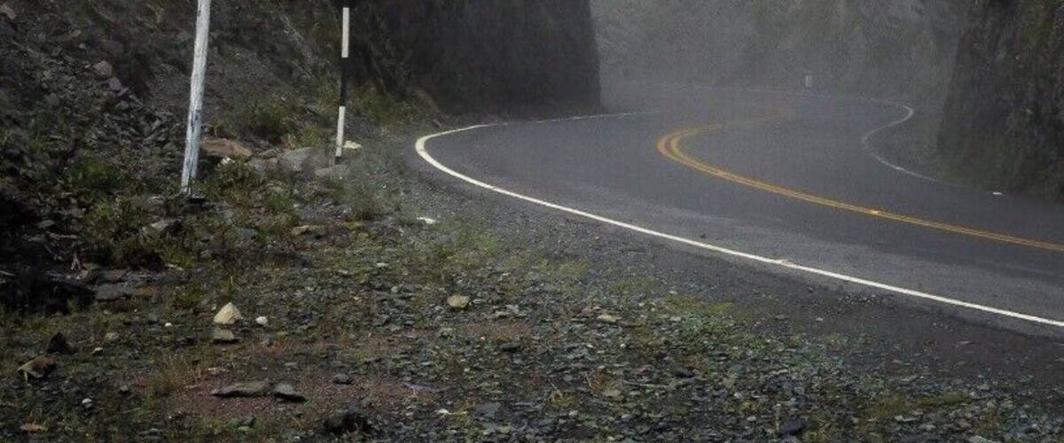 A winding mountain road with a warning sign for a steep descent.