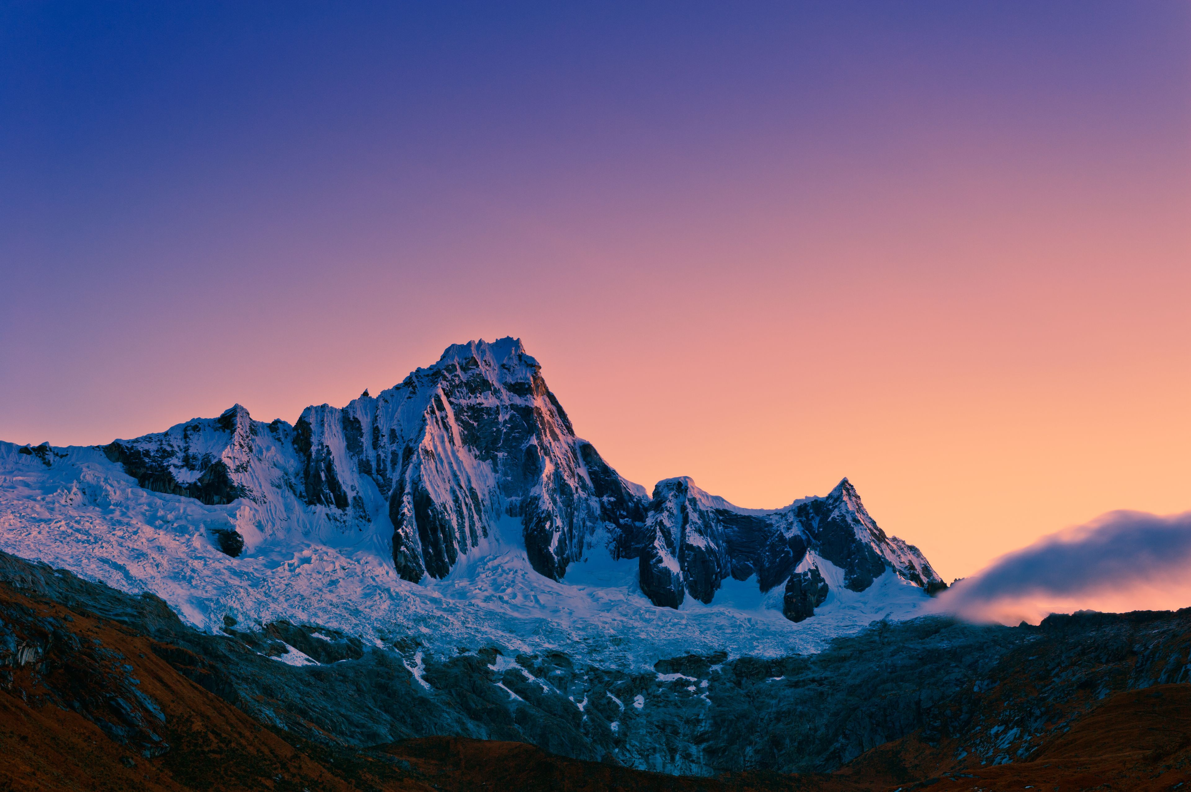 Een met sneeuw bedekte bergtop met scherpe richen en een heldere lucht in de schemering.