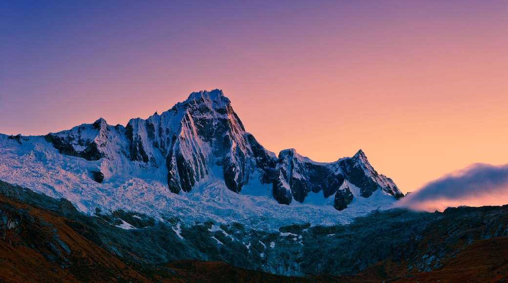 Een met sneeuw bedekte bergtop met scherpe richen en een heldere lucht in de schemering.