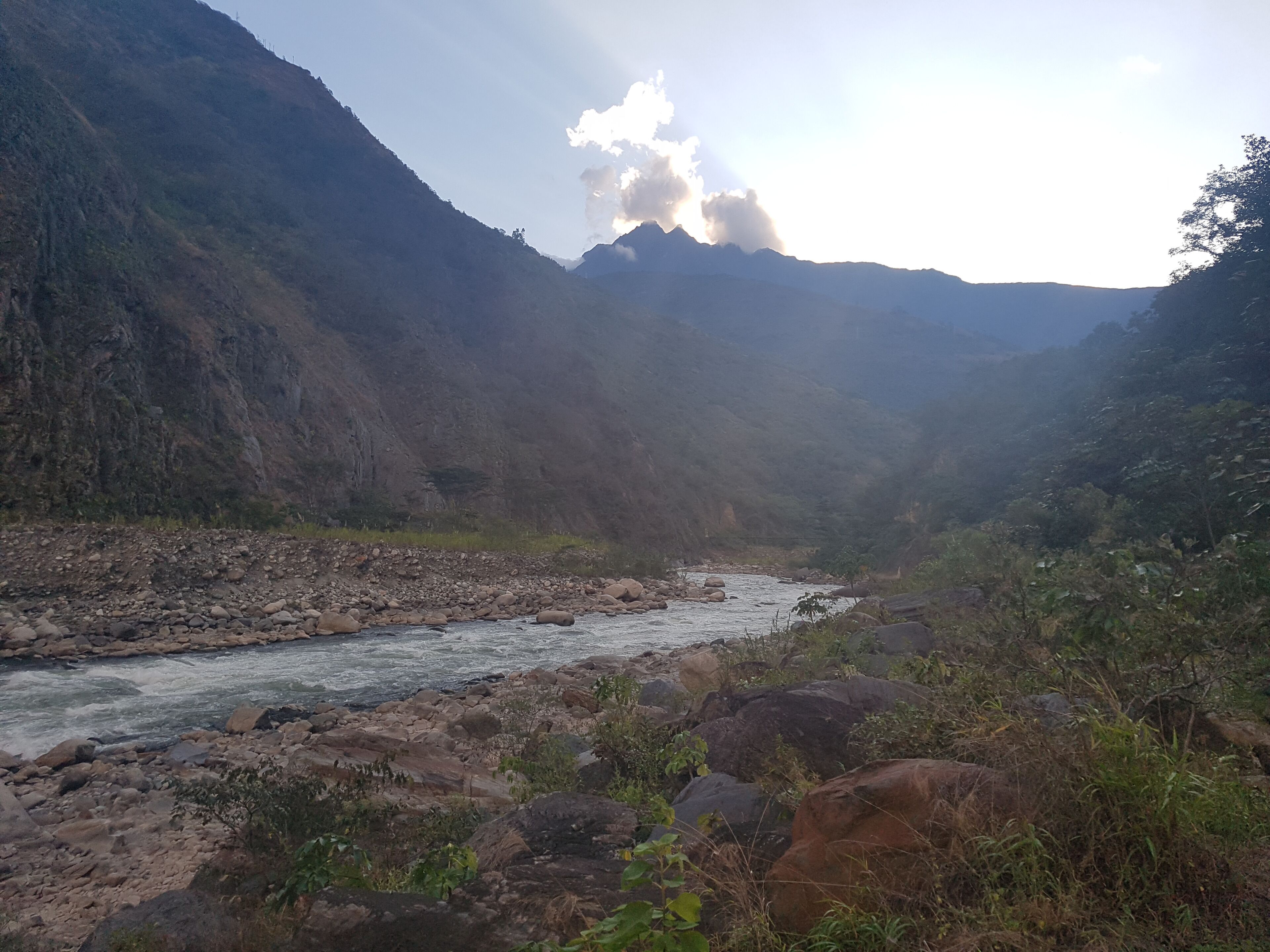 A river flowing through a rocky valley with mountains in the background.