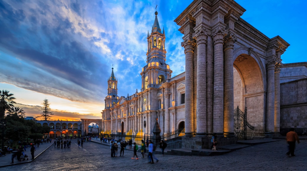 Una catedral histórica con dos torres gemelas y un gran arco, rodeada por una plaza empedrada con gente.