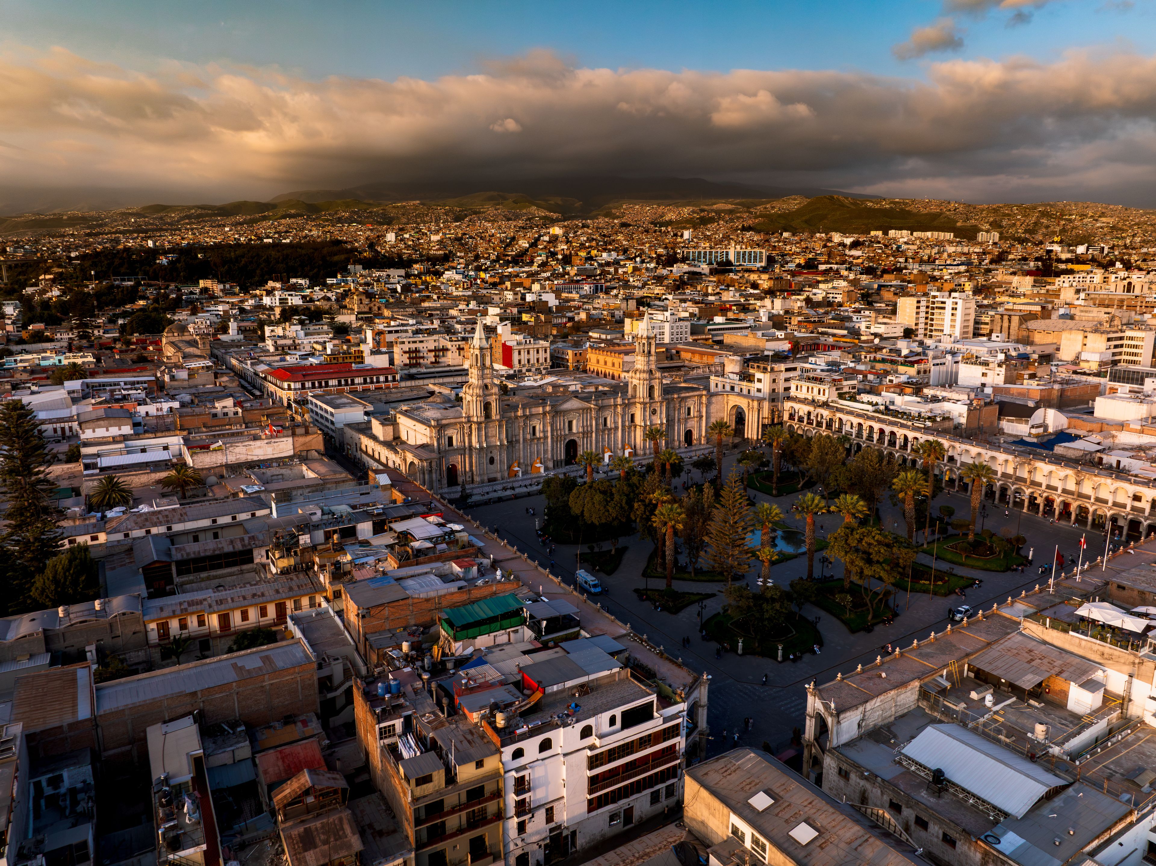Un paisaje urbano con una catedral destacada, edificios densos y un telón de fondo montañoso.