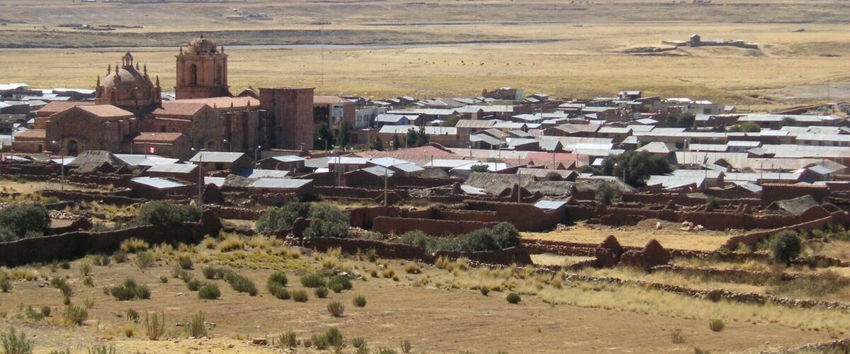 A town with a prominent church and mountains in the background.