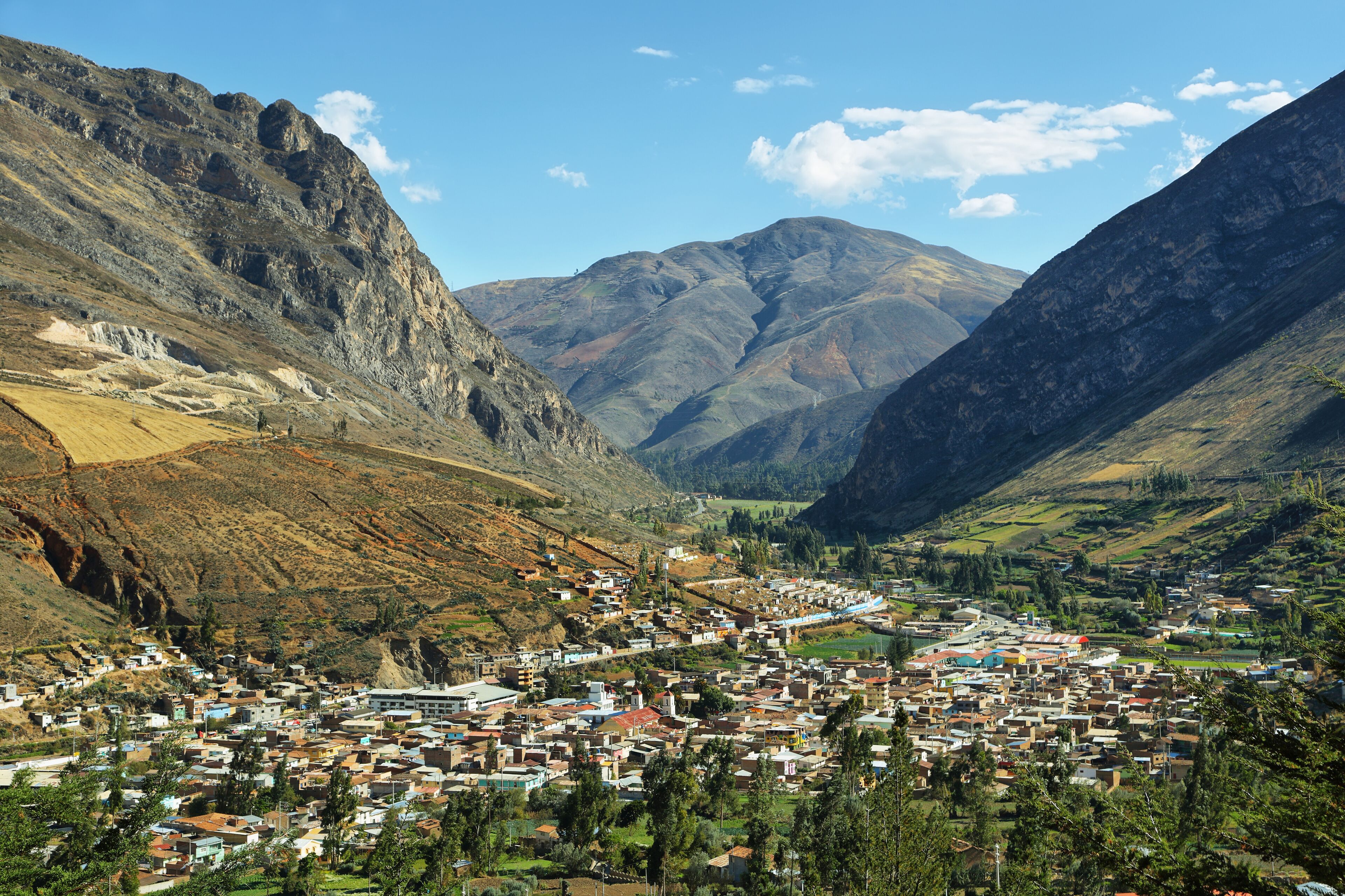 A mountainous town nestled in a valley with steep cliffs and a river.