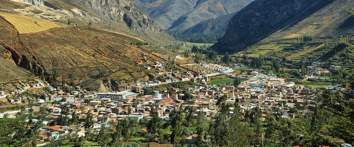 A mountainous town nestled in a valley with steep cliffs and a river.
