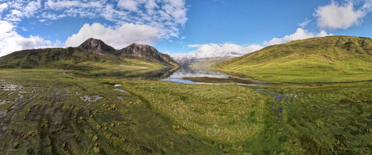 A mountainous landscape with a lake and green fields.