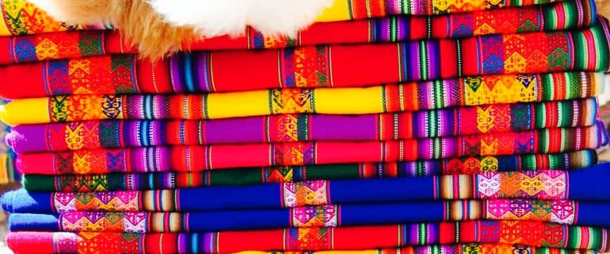A stack of colorful woven textiles with intricate patterns.