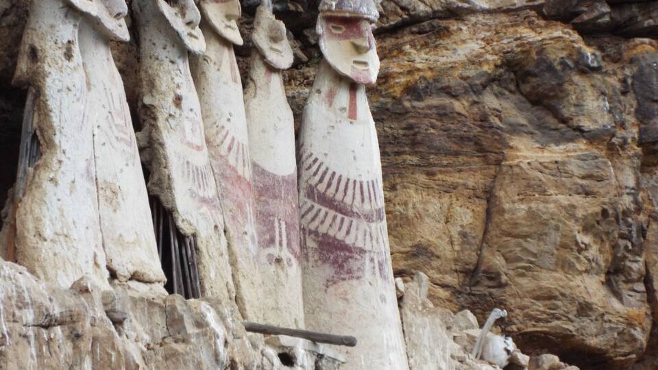 Carved stone figures with distinct facial features and patterns, set against a rocky background.