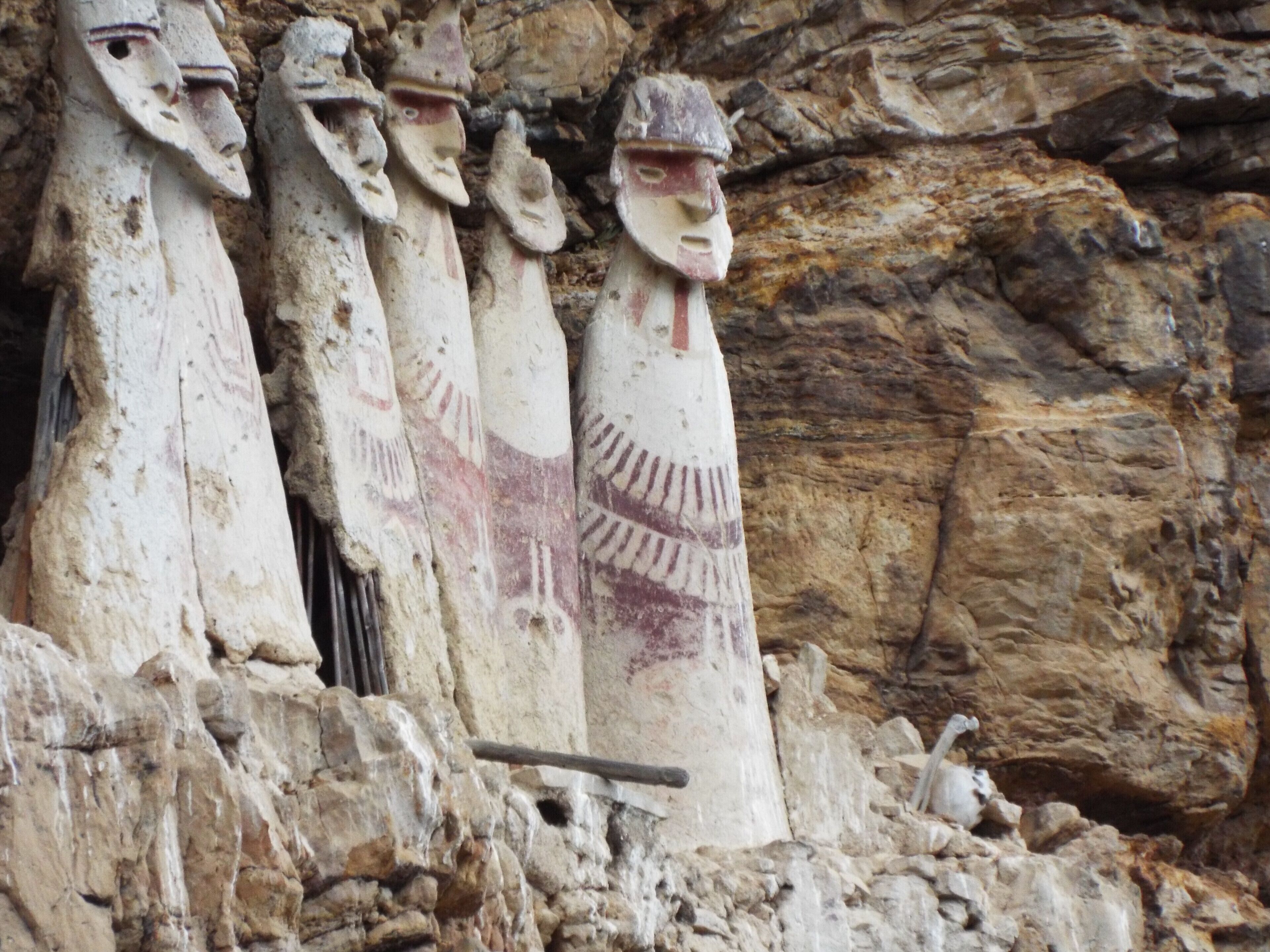 Carved stone figures with distinct facial features and patterns, set against a rocky background.