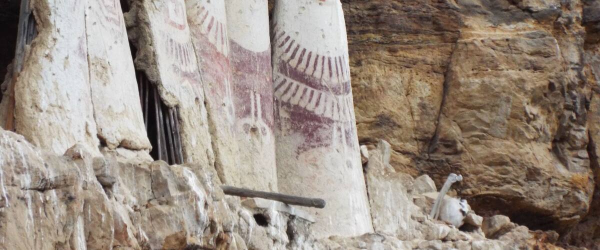 Carved stone figures with distinct facial features and patterns, set against a rocky background.