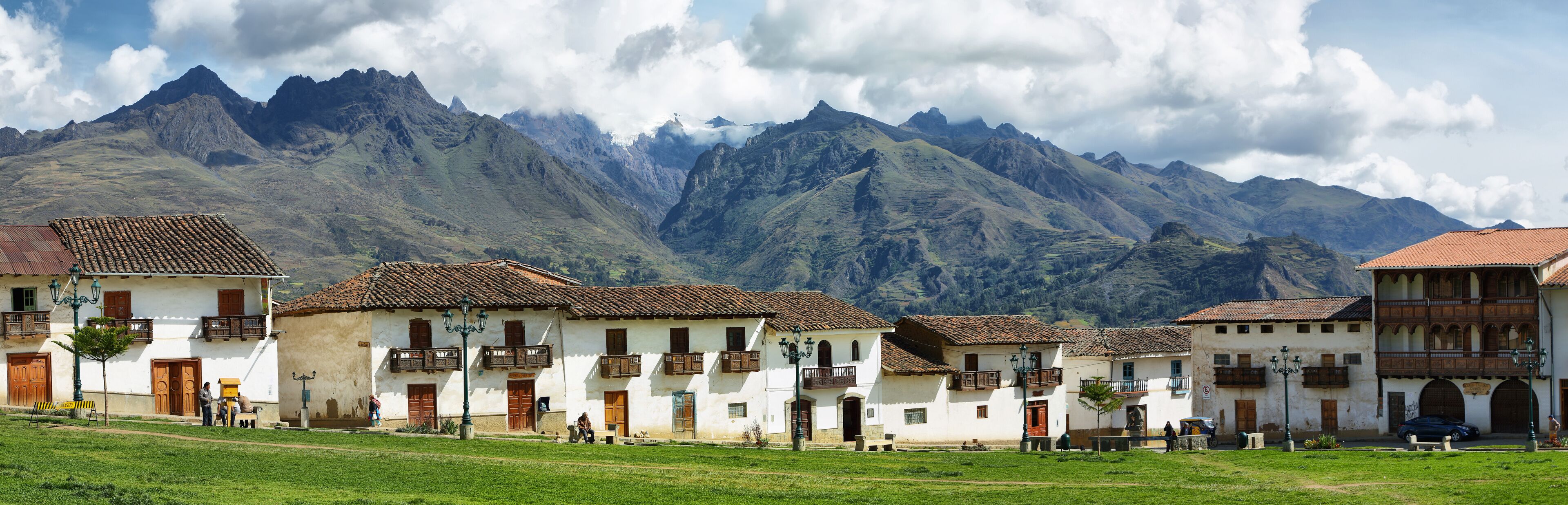 A village with white buildings and red-tiled roofs, surrounded by mountains.