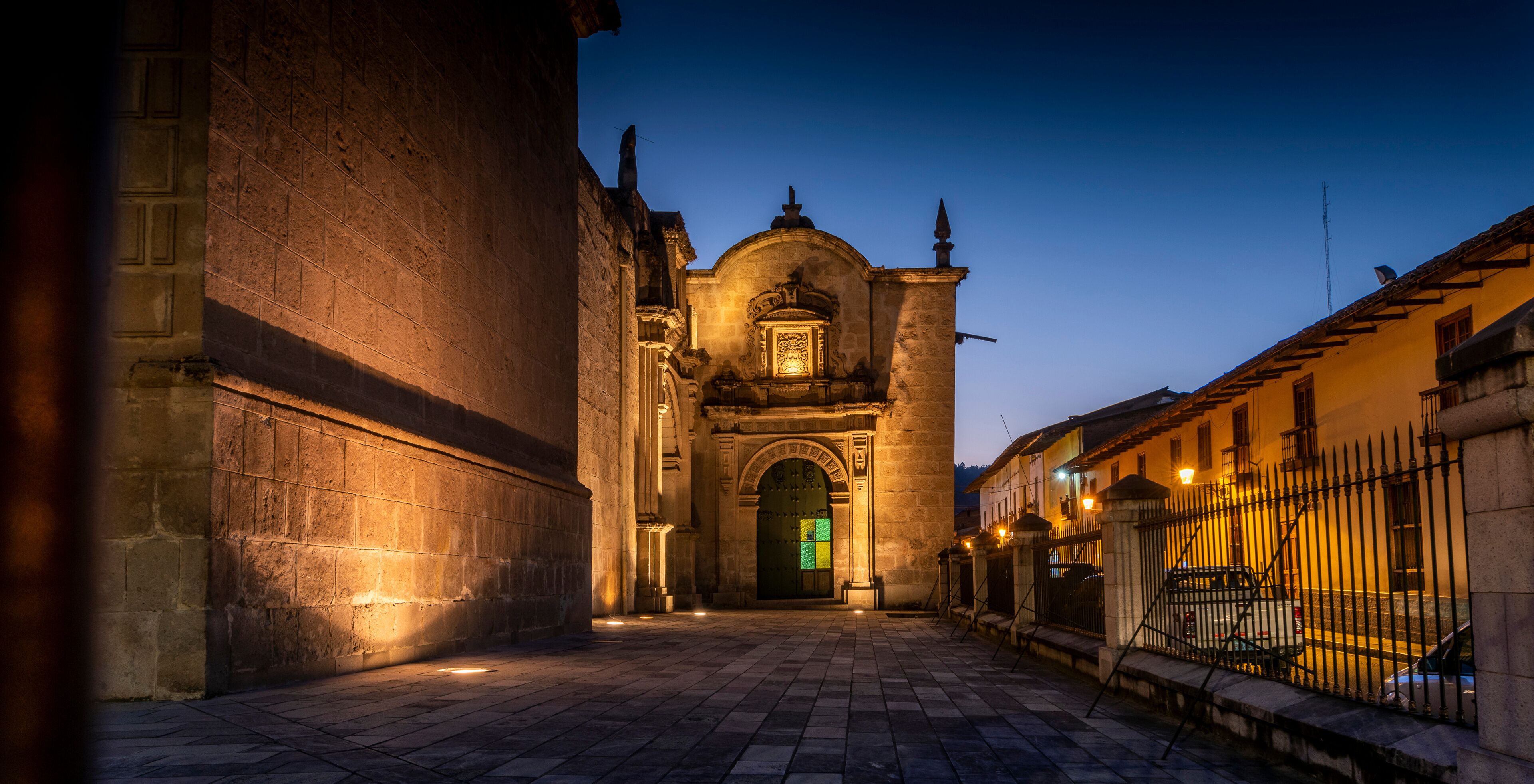 A historic building with a large arched entrance and a bell tower at dusk.