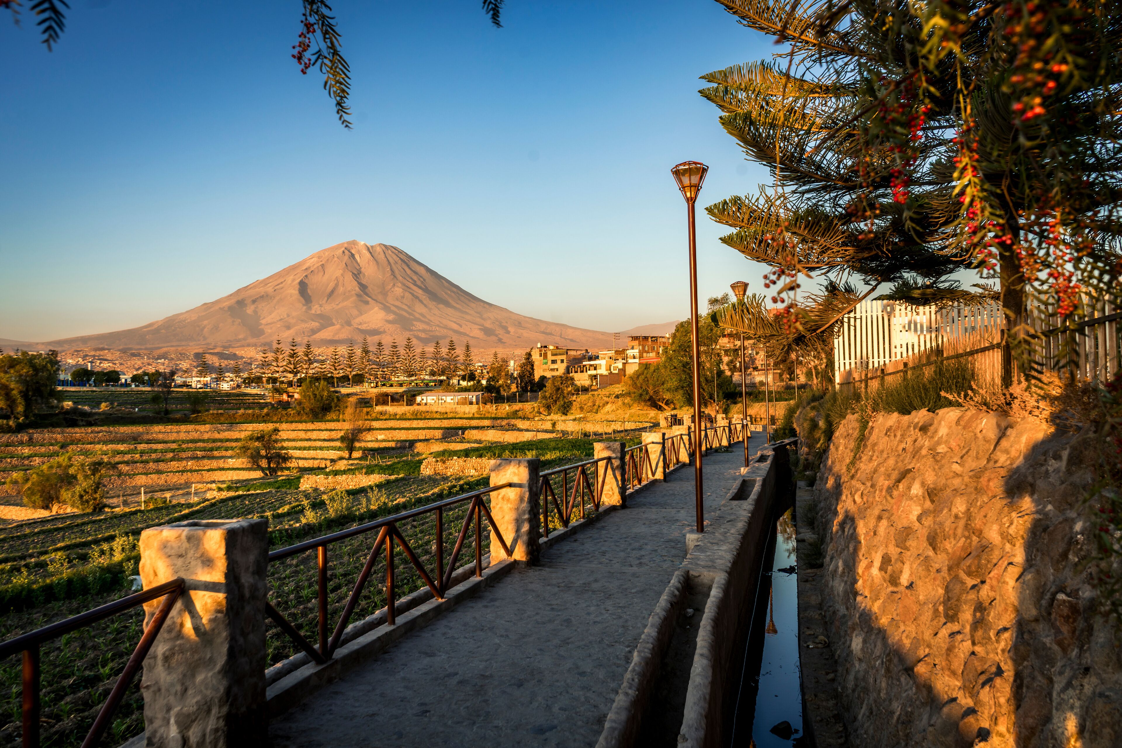 A mountain, a river, and a bridge with railings.