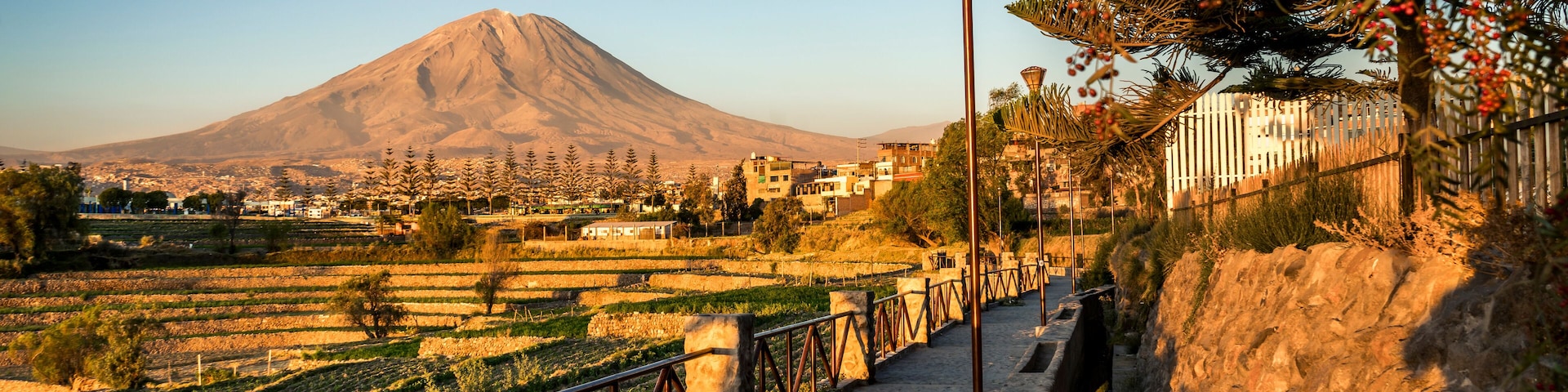 A mountain, a river, and a bridge with railings.