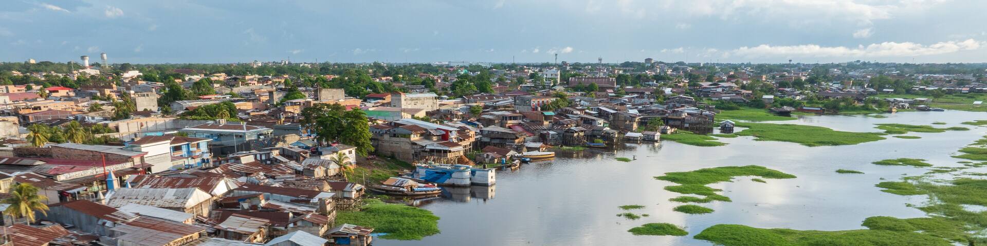 A river with floating houses and green vegetation.