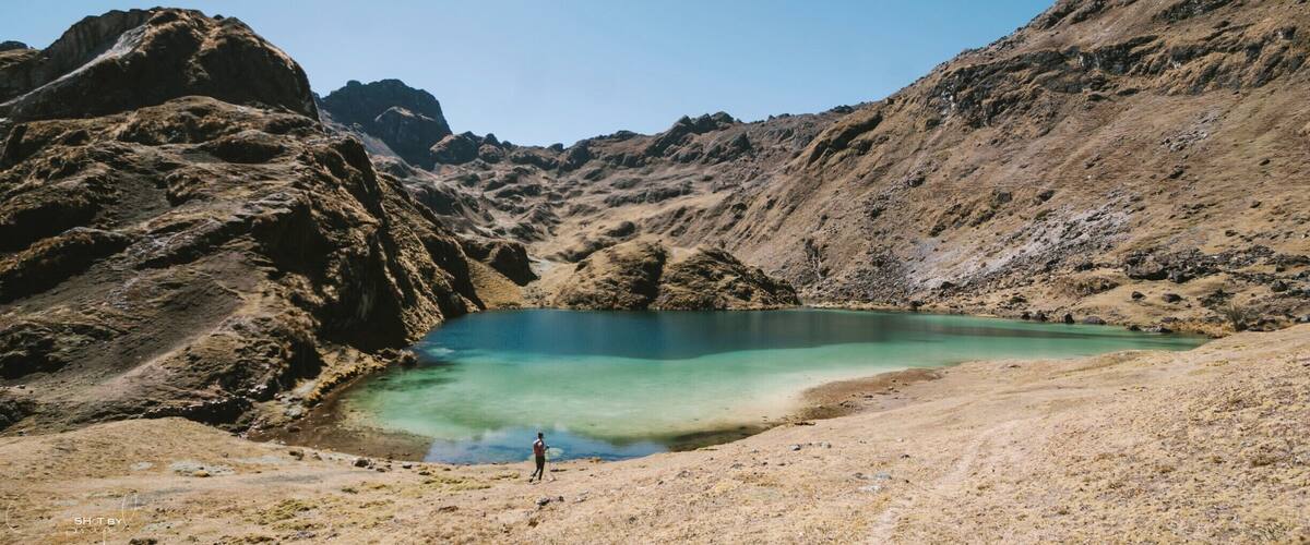 A mountainous landscape with a clear turquoise lake surrounded by rocky terrain.