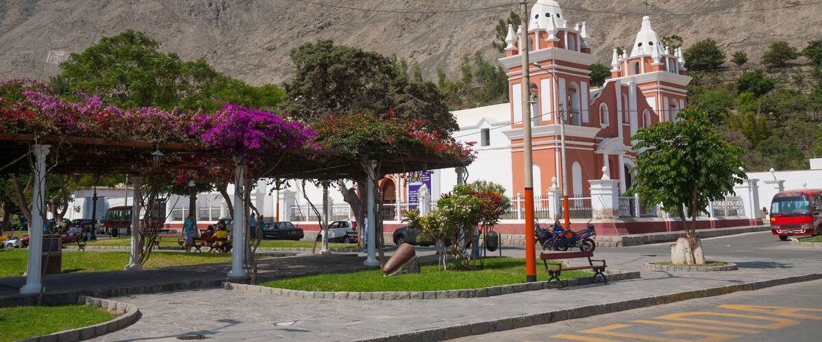A plaza with a church, a mountain, and a bus stop.