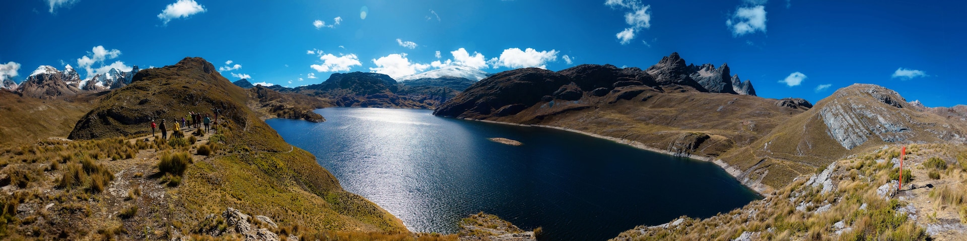 Un paisaje montañoso con un lago, terreno rocoso y cielo despejado.