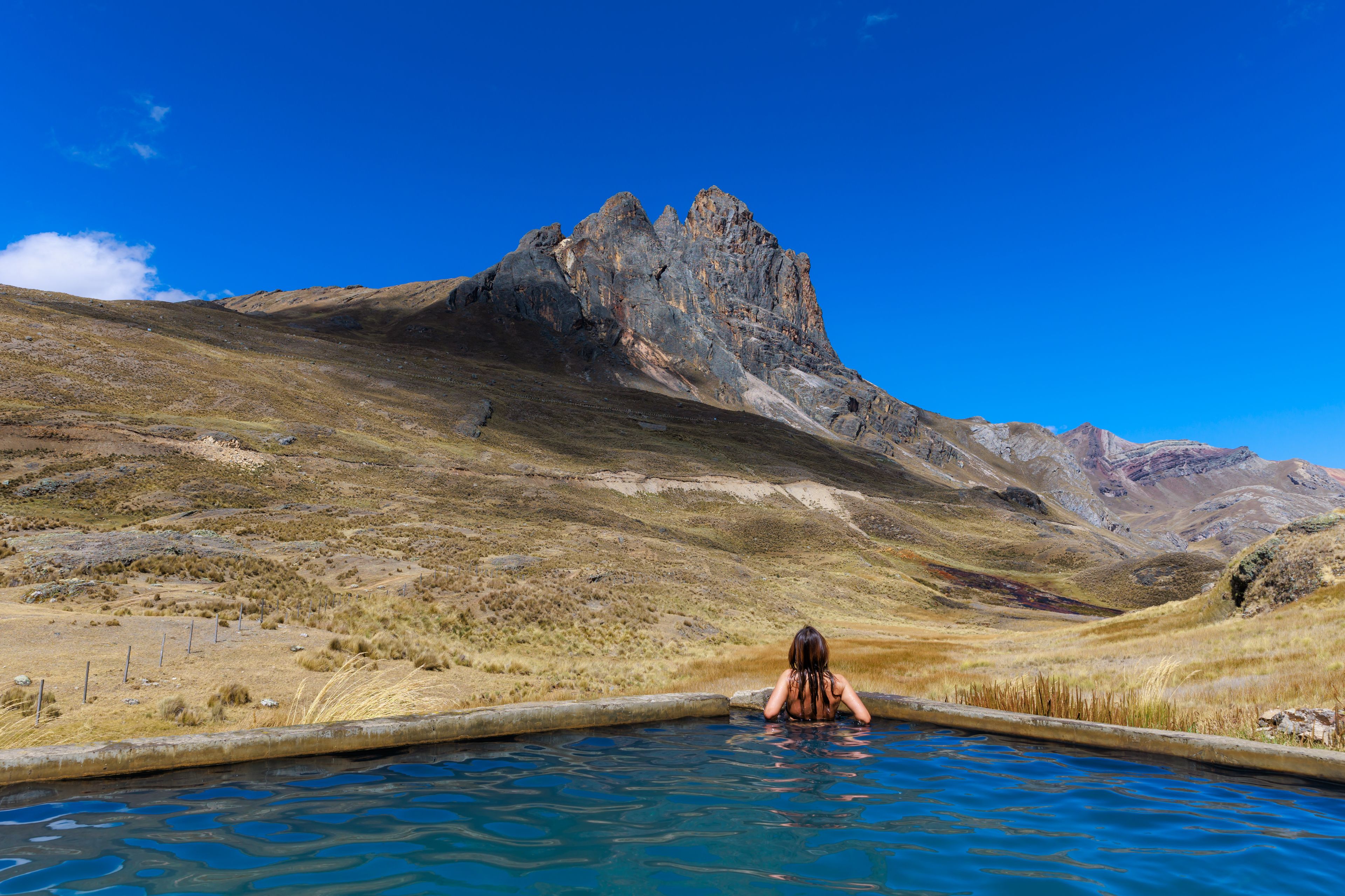 A person in a swimming pool with a mountainous landscape in the background.