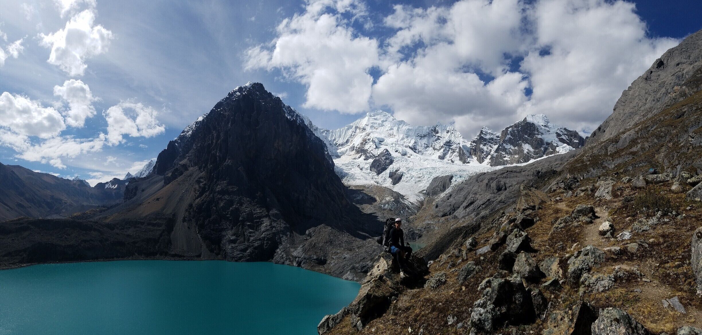A mountain peak, a turquoise lake, and a hiker.