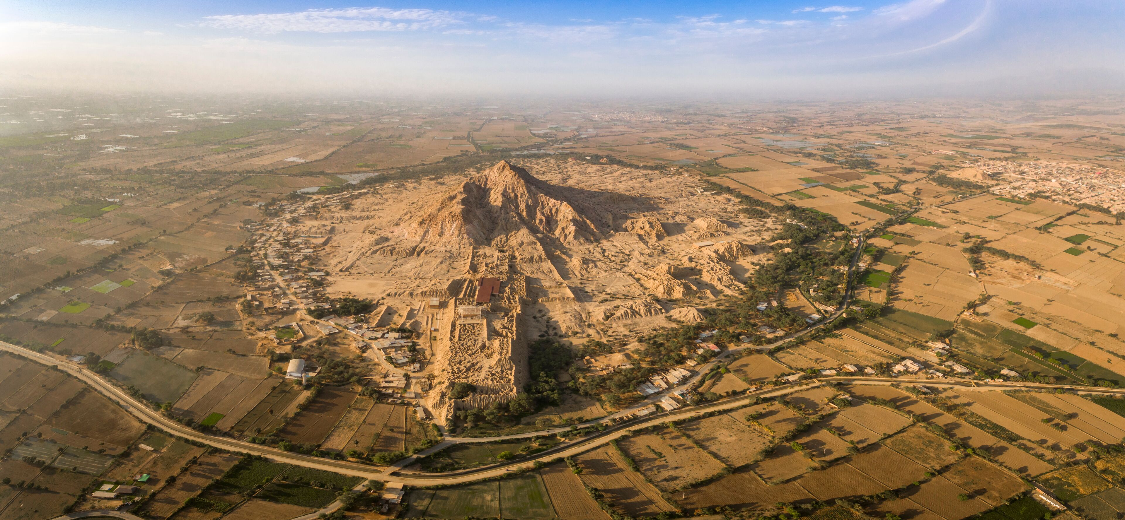 An aerial view of a pyramid-shaped mountain surrounded by agricultural fields and a small settlement.