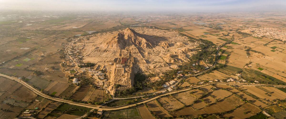 An aerial view of a pyramid-shaped mountain surrounded by agricultural fields and a small settlement.