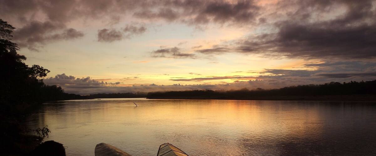 Un lac paisible au coucher du soleil, avec des bateaux amarrés sur la rive.