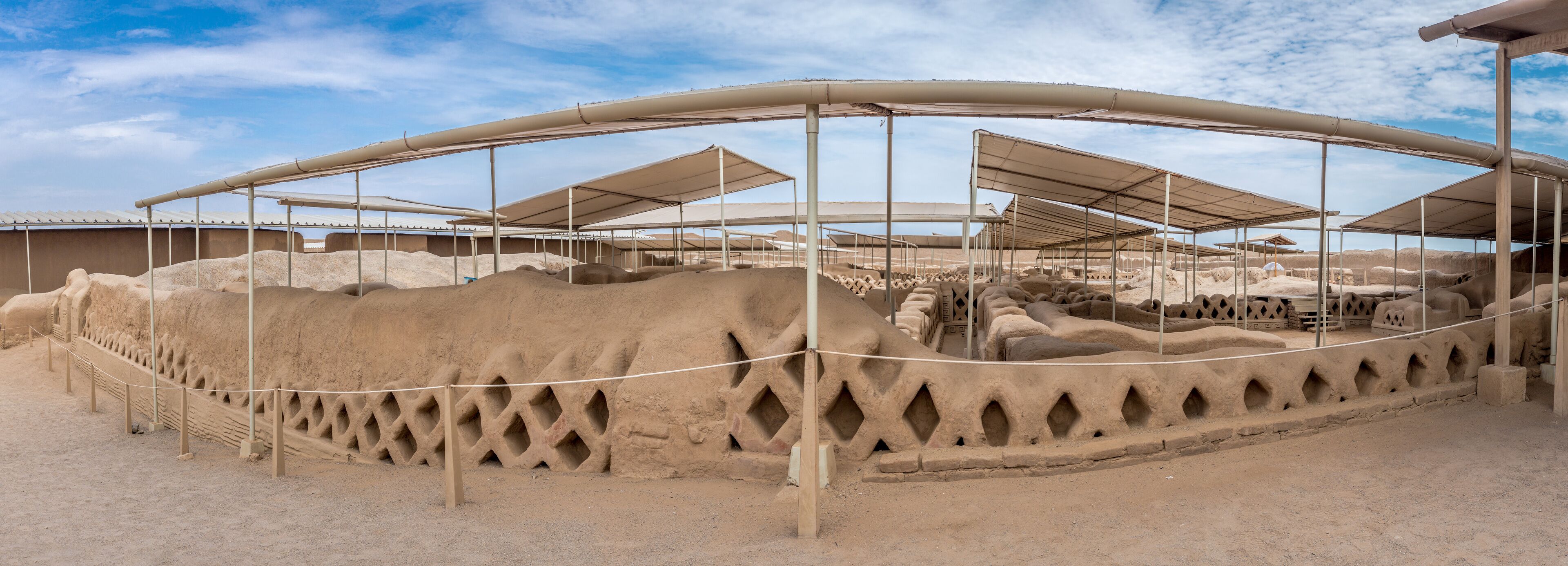 A large open area with multiple covered structures and piles of sand.