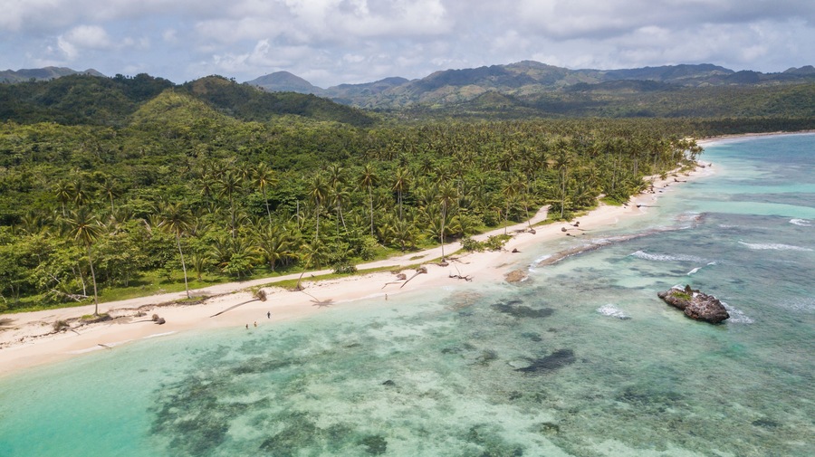 View of the ocean coast beach and mountains. Secluded white sand beach and mountains. Summertime Sea tranquility. Aerial view