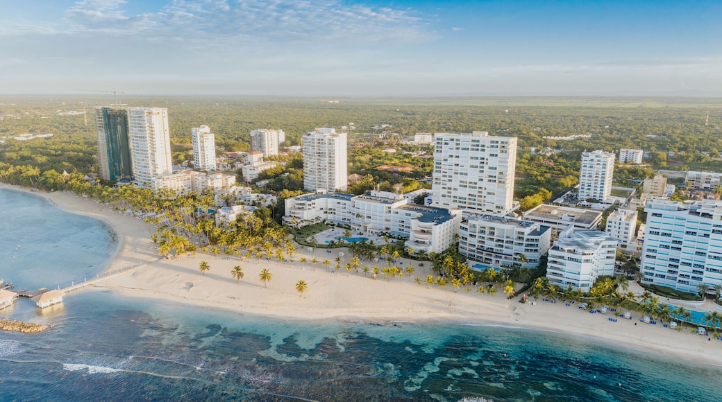 Aerial view of the coastal resort area of Juan Dolio, featuring high-rise buildings, sandy beaches, palm trees, and turquoise waters in Juan Dolio, San Pedro de Macoris, Dominican Republic.