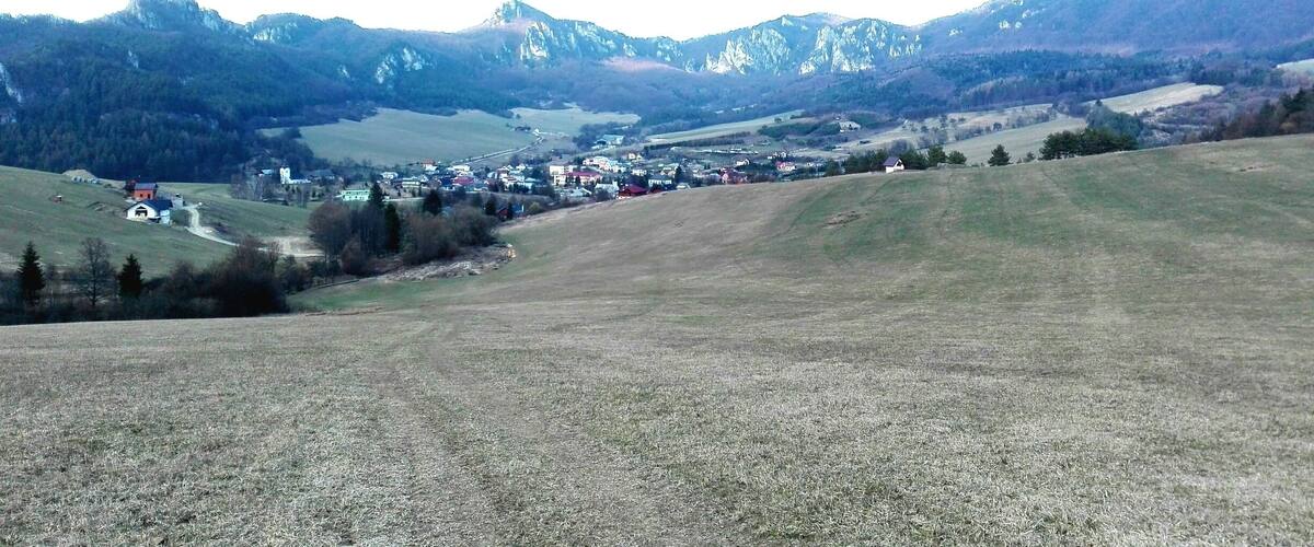 A rural landscape with a small village nestled in a valley, surrounded by mountains.