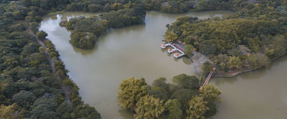 An aerial view of a river with a small island featuring a dock and a bridge.
