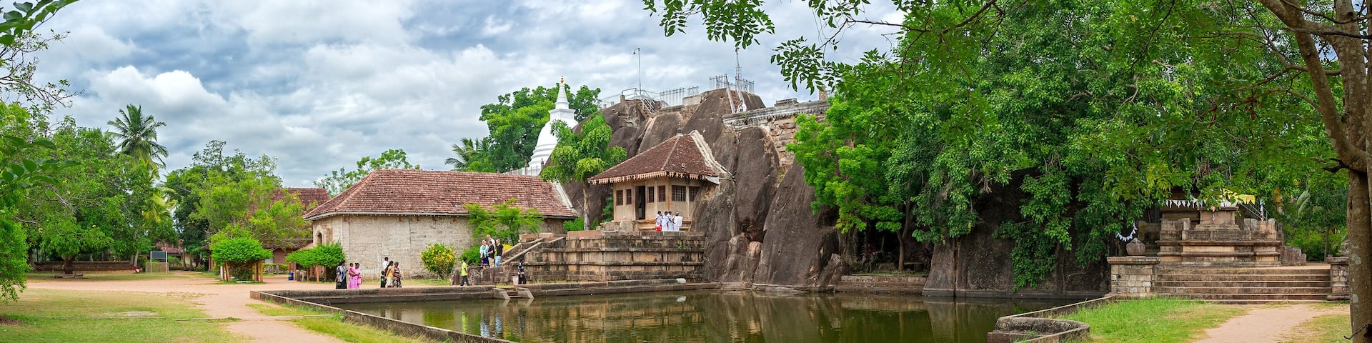 A temple complex with a pond, stone structures, and lush greenery.