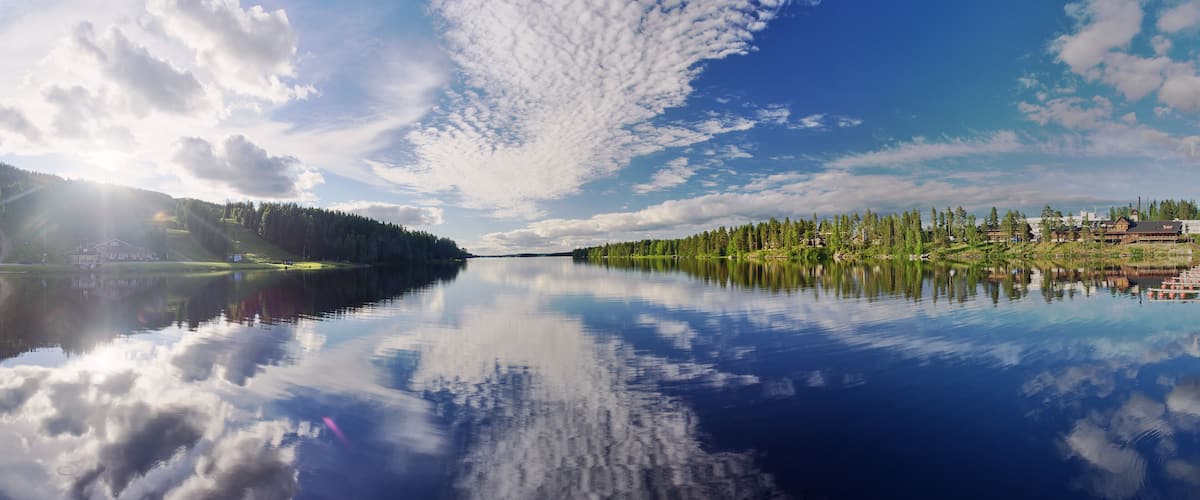 A calm lake reflecting the sky and surrounding trees.