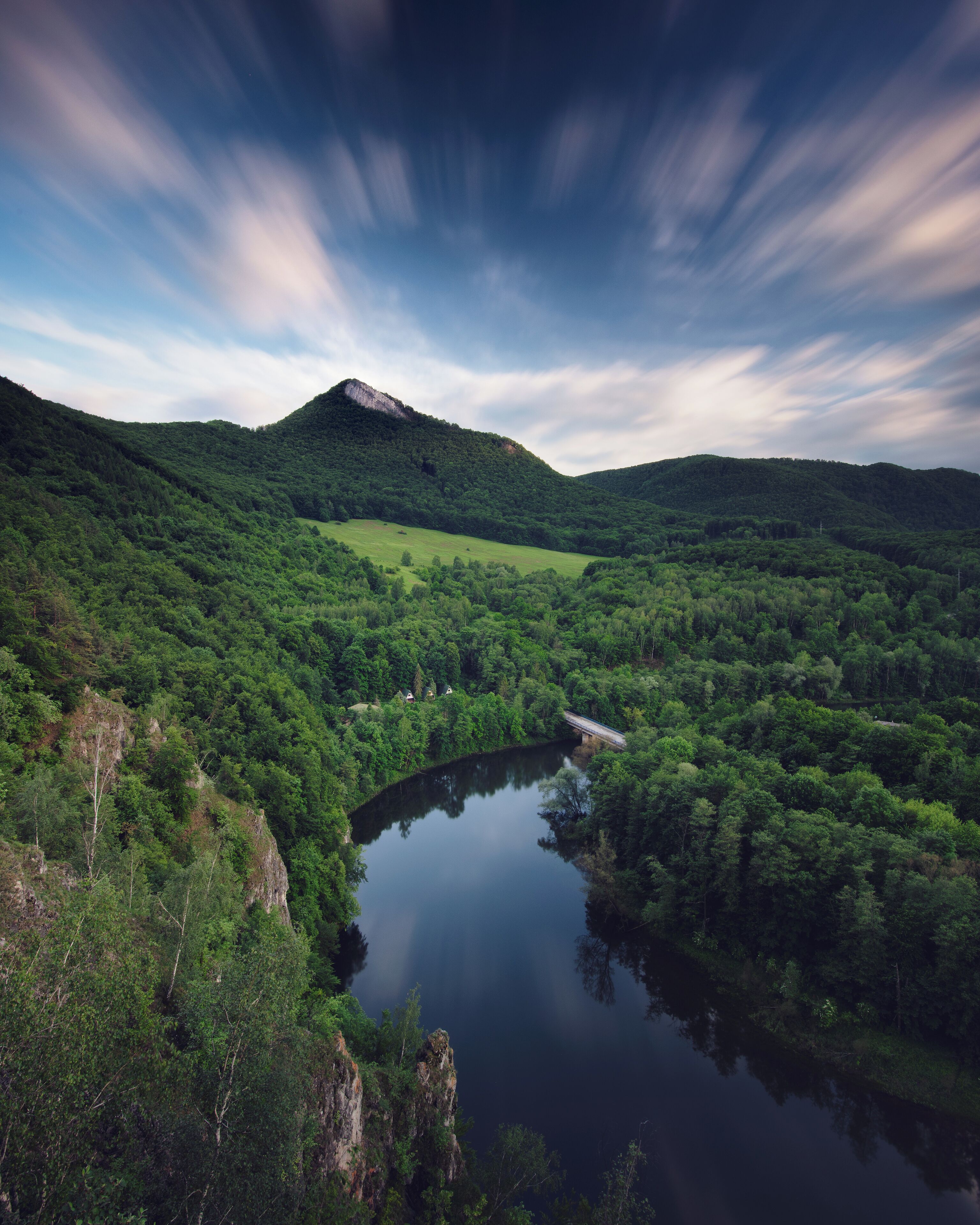 A river winding through a lush valley with dense forests and a mountain in the background.