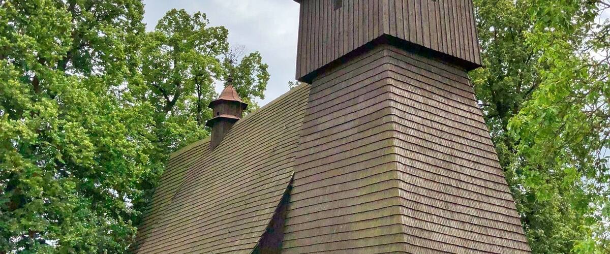 A wooden church with a steeply pitched roof and a bell tower.