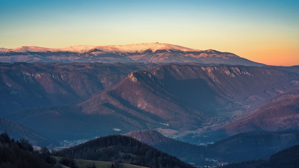 Une chaîne de montagnes aux sommets enneigés, avec une vallée en contrebas.