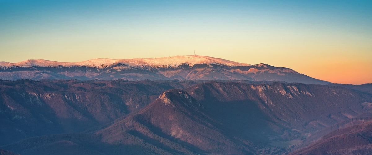 A mountain range with snow-capped peaks and a valley below.